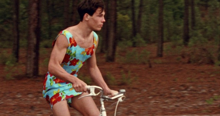 Young man on a bicycle wearing a blue summer dress